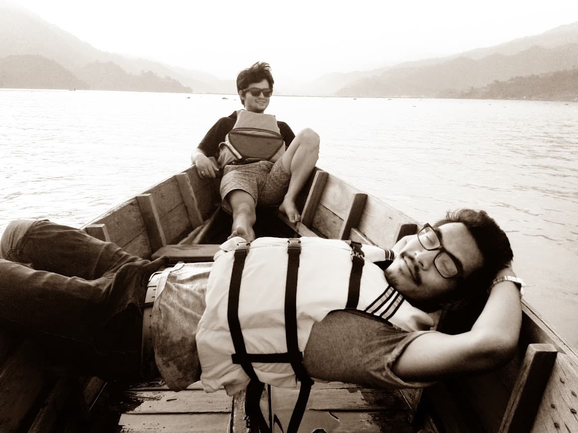 Milan and a companion relaxing in a wooden boat on a lake